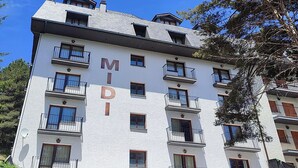 A multi-story hotel with balconies, a sign reading "MIDI", and a visible storefront with a sign that says "MIDI".