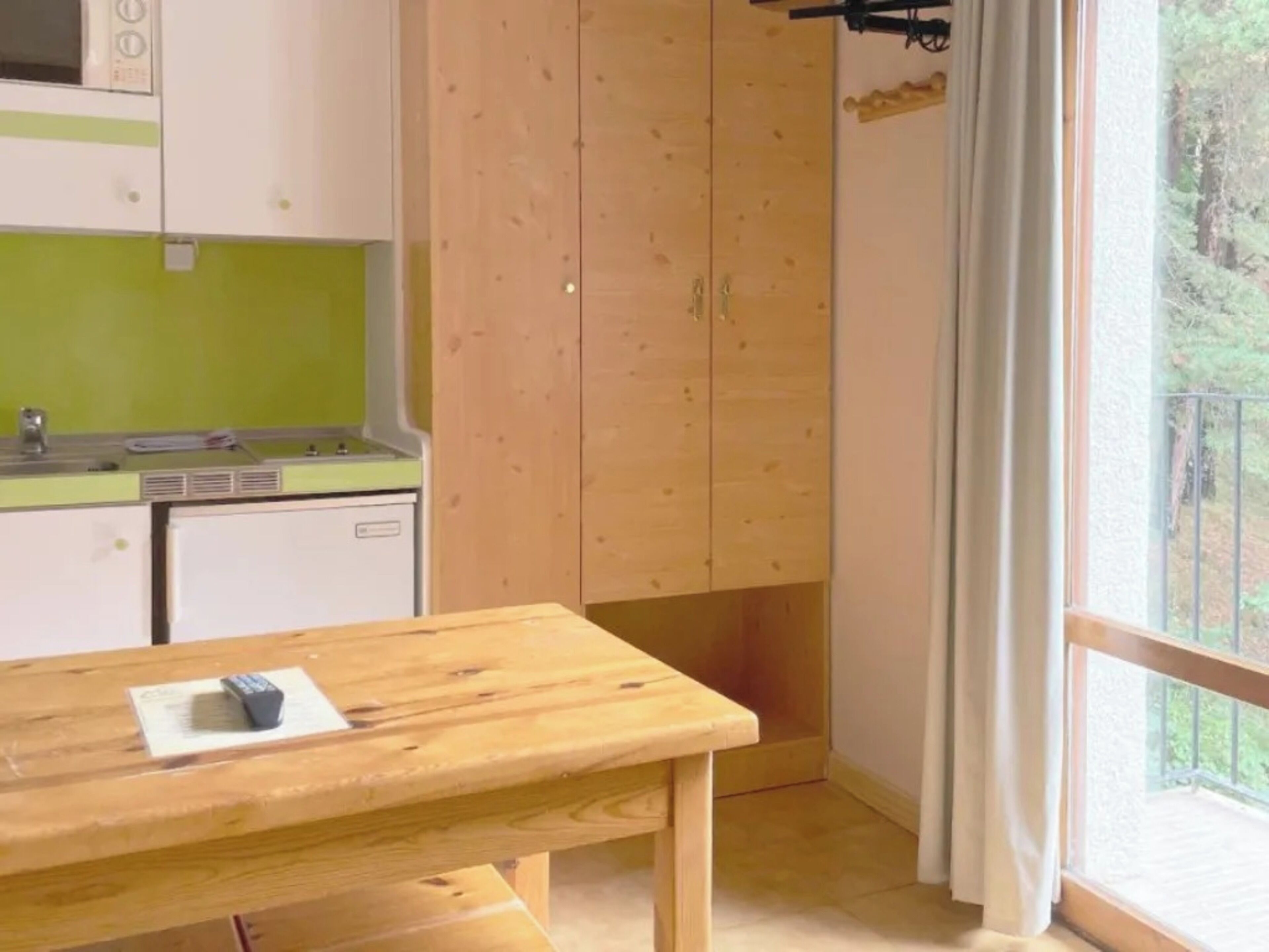 Une cuisine avec une table en bois, un petit évier et des placards.