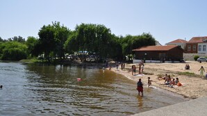 Een rivierlandschap met mensen die zwemmen en ontspannen op het zand.