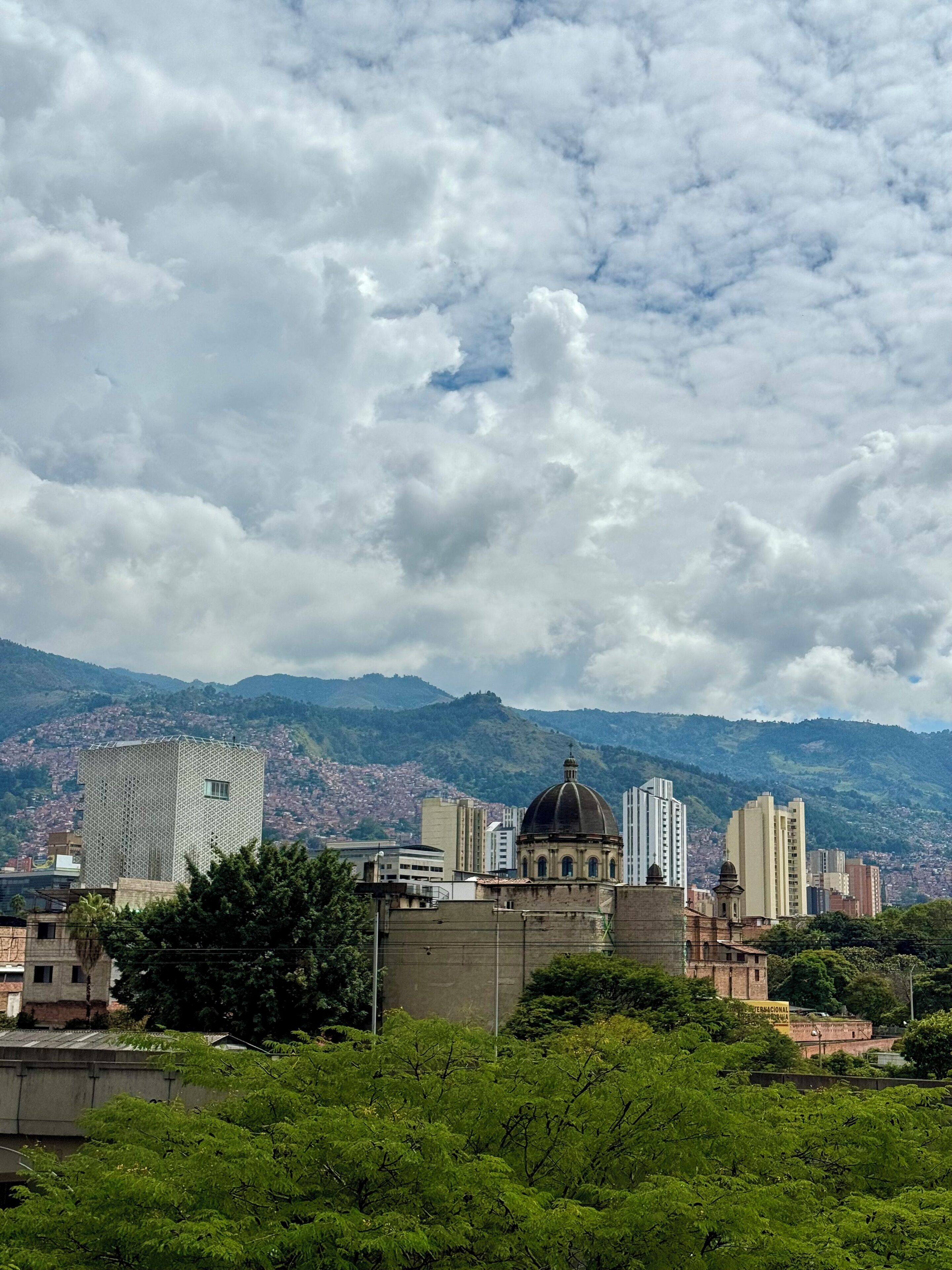 Une vue urbaine caractérisée par un dôme imposant, des bâtiments modernes et un paysage montagneux en arrière-plan.