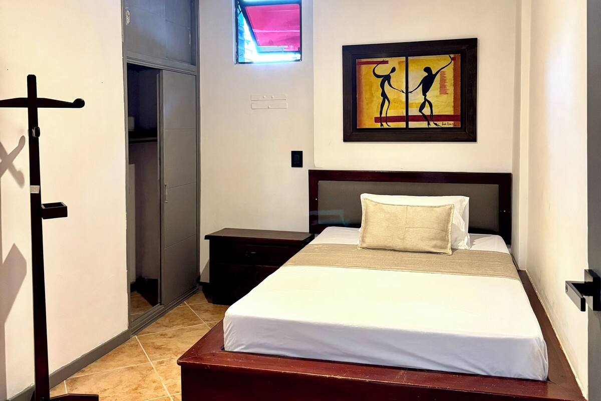 Une chambre d’hôtel avec un lit, une table de chevet, une armoire et un tableau au mur.