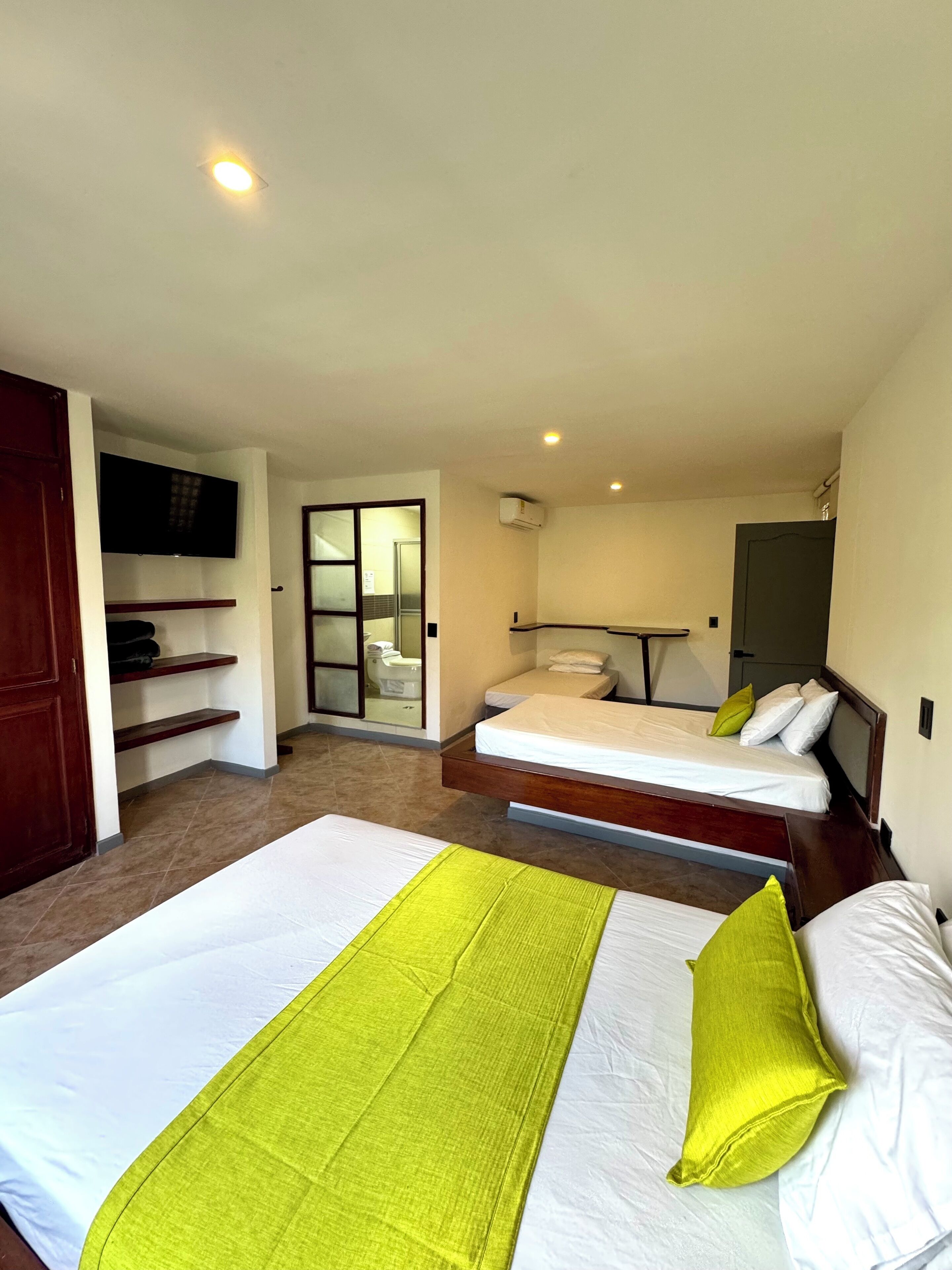 Une chambre d’hôtel avec deux lits, une télévision, une salle de bain et une porte coulissante.