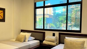 Habitación de hotel con dos camas, un ventanal con vistas a la ciudad y un cuadro en la pared.