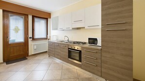 Una cocina con estufa, horno y microondas, armarios de madera y una ventana.