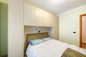 A bedroom with a bed, a headboard, a wardrobe, and a door.