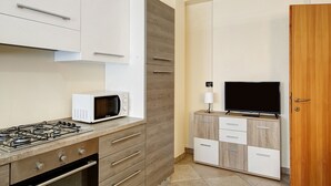 Una cocina con estufa a gas, microondas y armarios de madera.