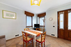 A dining area with a table, chairs, a television, and a clock on the wall.