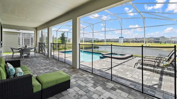 A covered patio area with a pool, outdoor furniture, and a view of a residential complex. - 9BR Lakeview Villa - Pool, Jacuzzi & Pool Table! (Kissimmee)