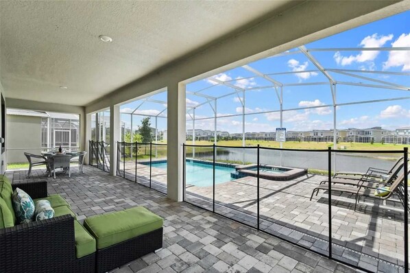 Un espacio cubierto con piscina, mobiliario exterior y vistas a un conjunto residencial.
