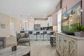 A modern kitchen with white cabinets, a central island, and bar stools.