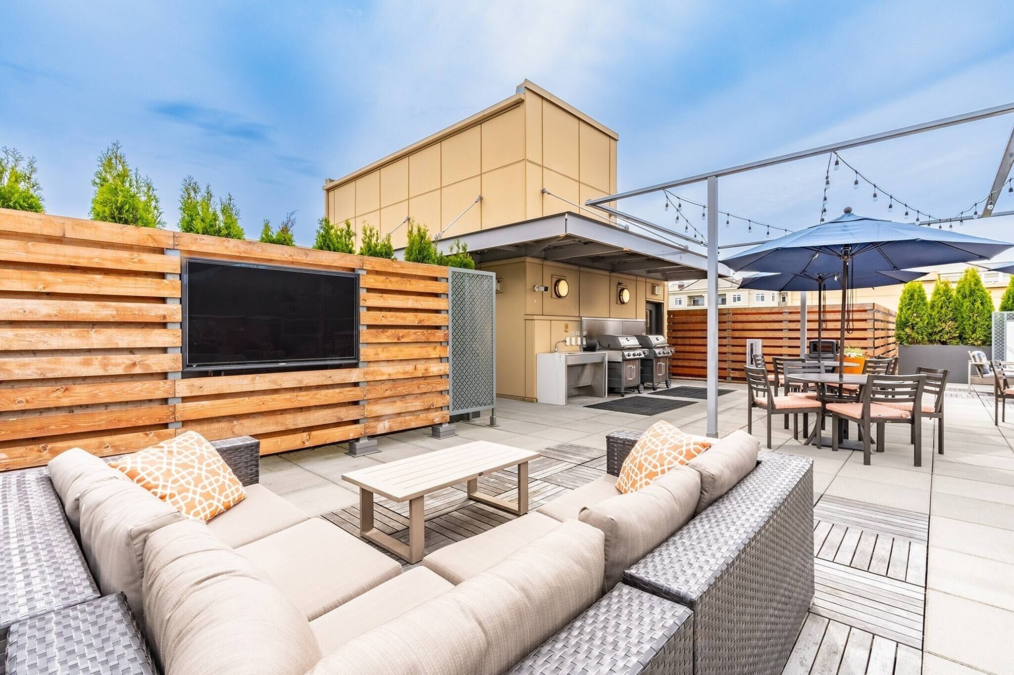 Une terrasse extérieure équipée d’un téléviseur, d’un barbecue et d’un espace salon.