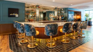 A bar area with a central island, bar stools, and a tiled floor. - 1BR | Gym, Views | Bellevue | Sophari Parkside C (Bellevue)