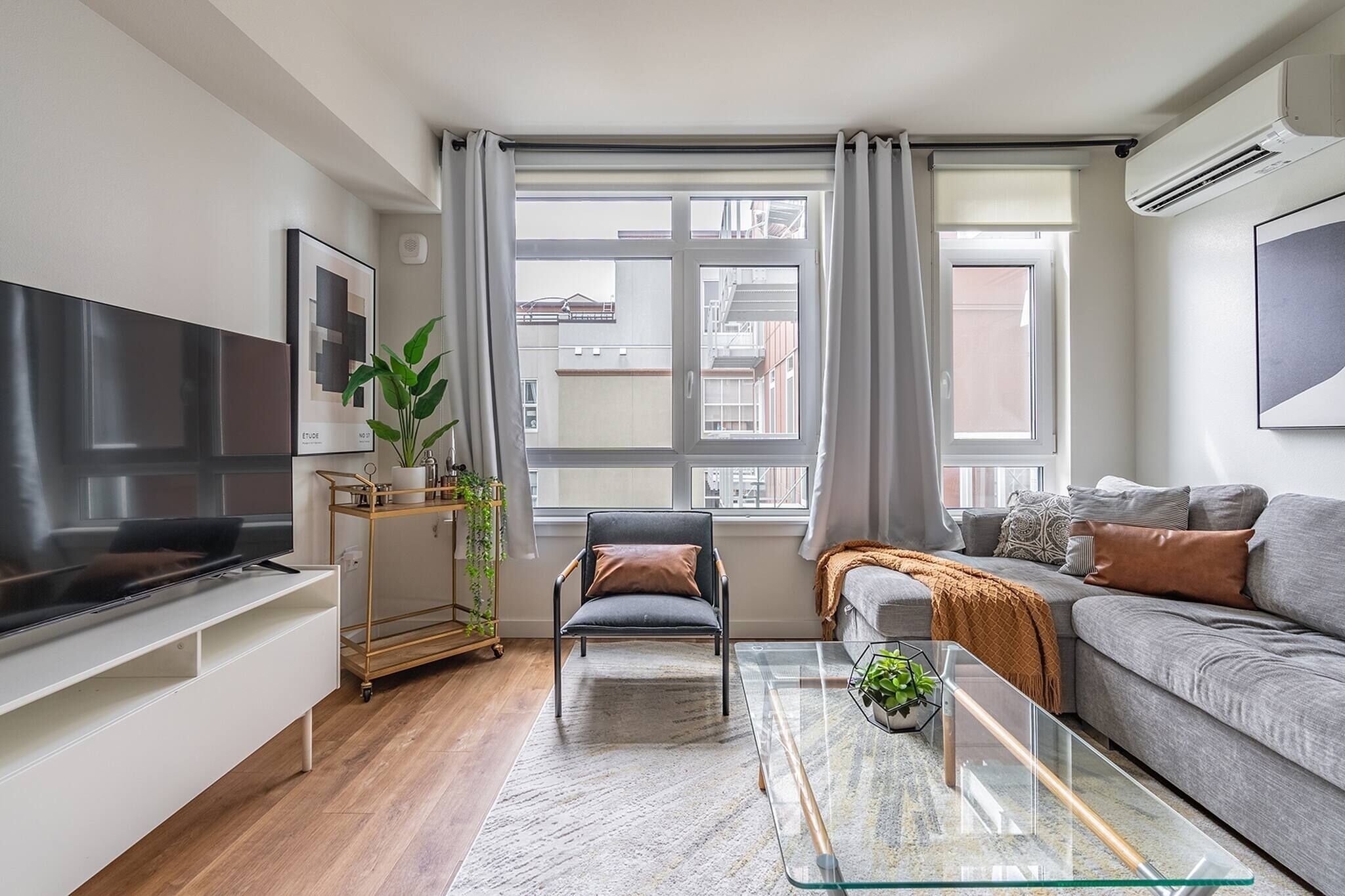 A modern living room with a flat-screen TV, a sofa, a glass coffee table, and a chair.