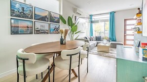 A modern living room with a dining area, large windows, and a view of the city. - 3BR | Rooftop | West Seattle | Sophari Home B (Seattle)