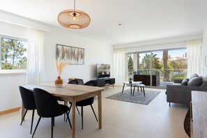 Ein modernes Wohnzimmer mit Essbereich, großen Fenstern und einem Balkon.