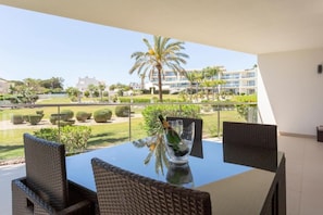 Ein Balkon mit Korbstühlen, einem Tisch und einer Champagnerflasche.