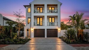 A modern two-story house with a flat roof, two balconies, and a garage. - Luxury Lido Retreat with Pool, Spa, Firepit & Rooftop Views (Sarasota)