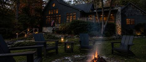 A cabin with a fire pit, outdoor seating, and a stone staircase leading to the entrance.