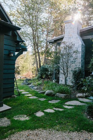 A well-maintained garden with a stone pathway leading to a stone building. - Boathouse: Lakefront Highlands Retreat | Canoe + Gated (Highlands)