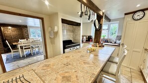 Een moderne keuken met een groot kookeiland, een eethoek met een bakstenen muur en uitzicht op het buitengebied.