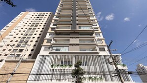 A high-rise building with multiple balconies, a central vertical feature, and a clear sky. - Studios in Building With Gym in Brooklin - SP Emnrs (São Paulo)