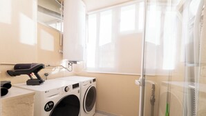 A laundry area with two washing machines, a dryer, and a glass shower stall. - Your Dream Vacation (Marbella)