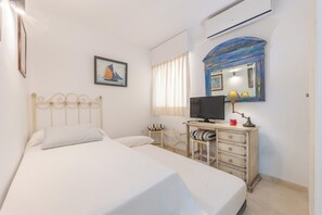 Quarto de hotel com cama, televisão, cómoda e janela com cortinas.