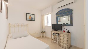 A bedroom with a bed, a desk, a chair, a television, a mirror, and a window. - Your Dream Vacation (Marbella)