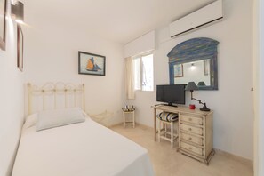 A bedroom with a bed, a desk, a chair, a television, a mirror, and a window. - Your Dream Vacation (Marbella)