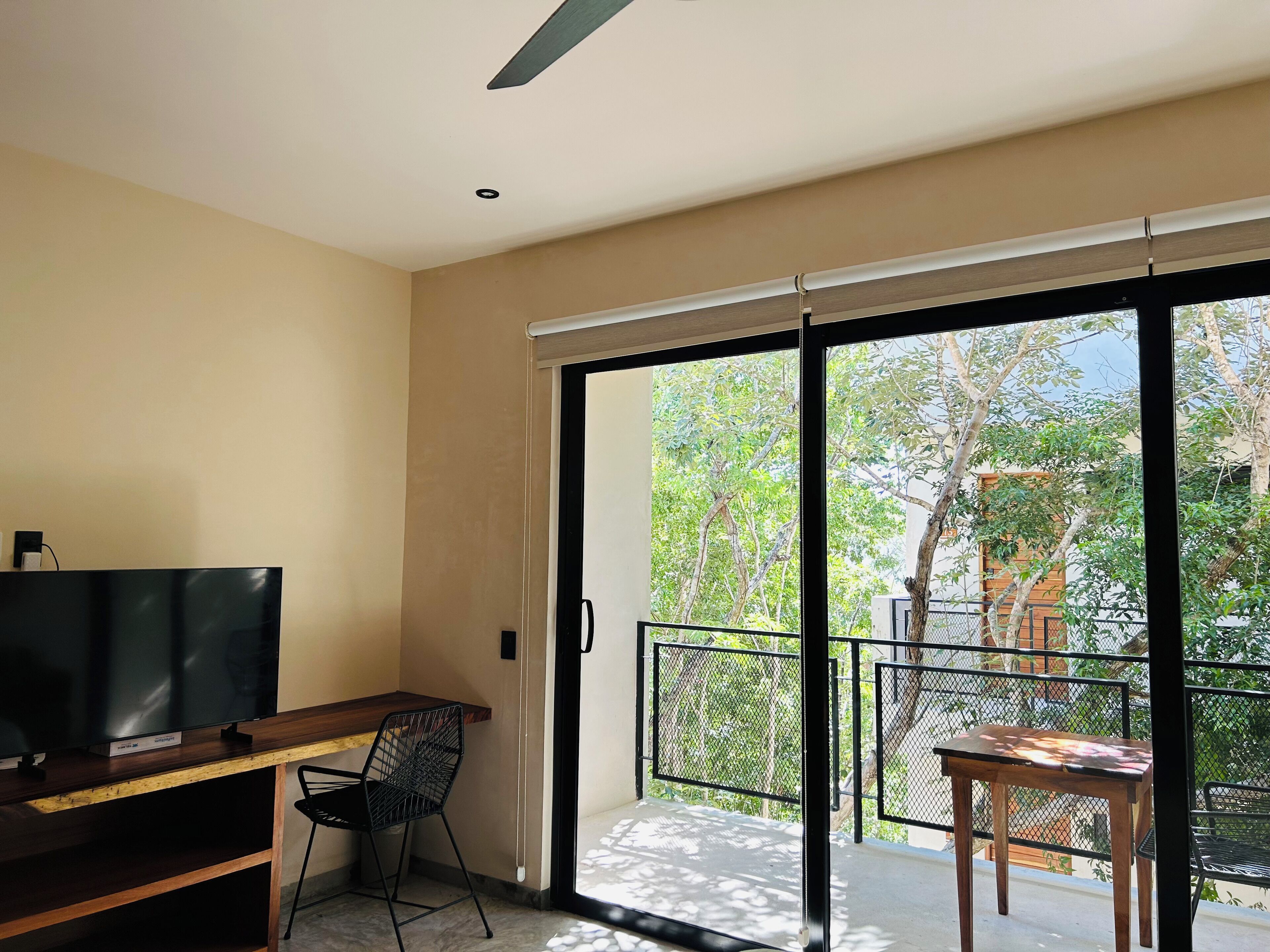 Quarto moderno com televisão de tela plana, escrivaninha de madeira e cadeira preta.