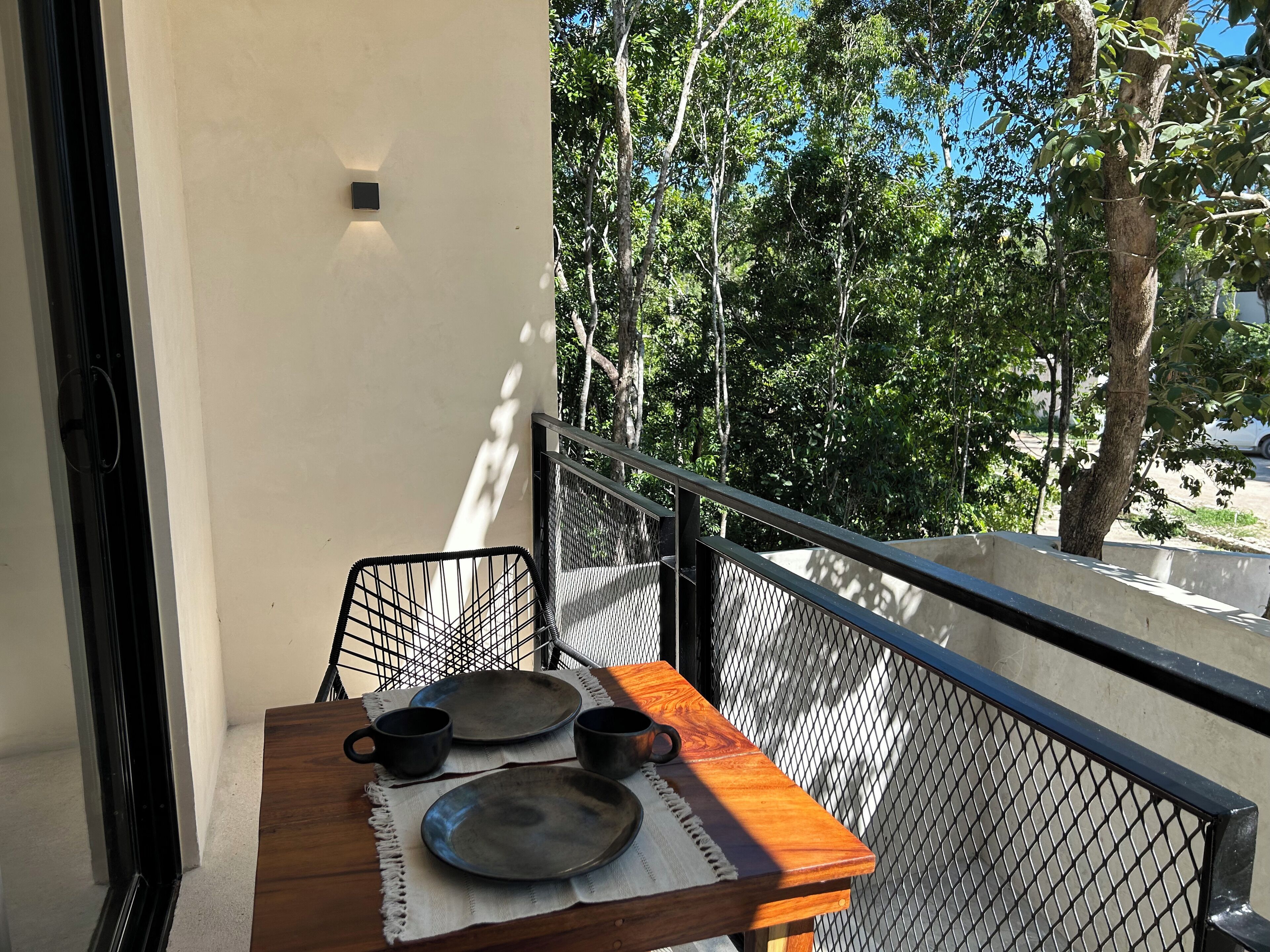 A balcony with a wooden table, two chairs, and a metal railing.