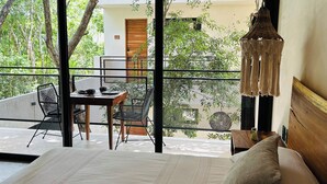 Ein Schlafzimmer mit einem großen Bett, einem Holz-Kopfteil und Blick auf einen Balkon mit Tisch und Stühlen.