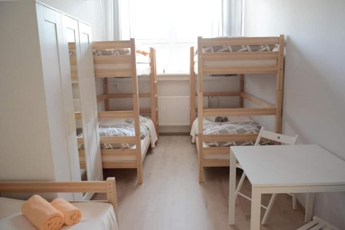 A room with bunk beds, a small table, and a wardrobe.