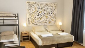 A hotel room with a bunk bed, a sofa, a small table with a plant, and a large abstract painting on the wall. - T10 Self check-in Hotel (Hafnarfjörður)