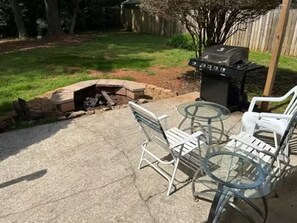 Une terrasse avec un foyer, des sièges d’extérieur et un barbecue.