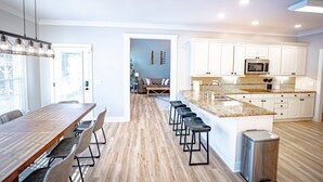 A modern kitchen with white cabinets, a granite countertop, and a stainless steel sink. - Luxury Golf Retreat - Simulator & Short Game Setup (Southern Pines)