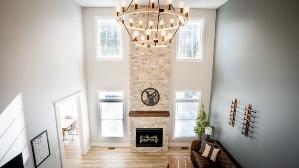 A spacious living room with a fireplace, a chandelier, and a wall-mounted coat rack. - Luxury Golf Retreat - Simulator & Short Game Setup (Southern Pines)