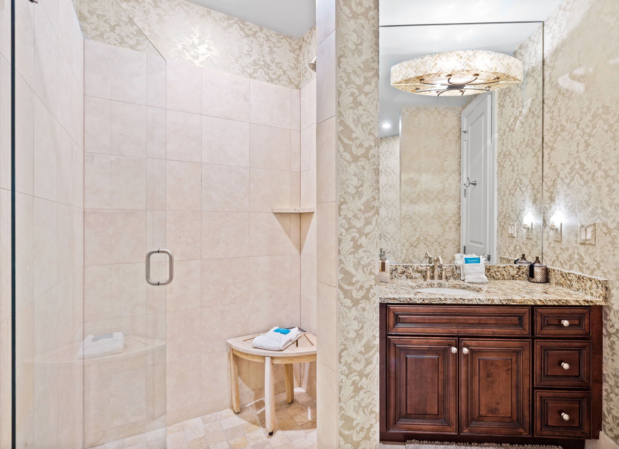 A bathroom with a shower, vanity, and a large mirror.