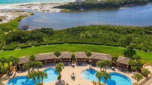 Een resort met meerdere zwembaden, een strandfront en weelderige begroeiing.