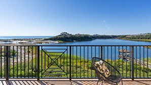 Een balkon met uitzicht op een meer, een stoel en een klein prieeltje.