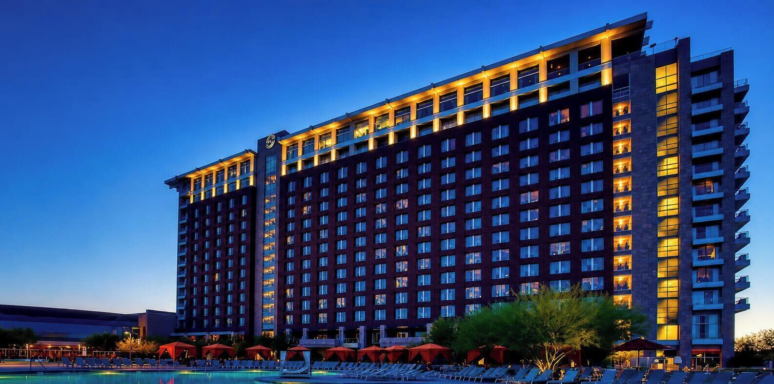 A high-rise hotel with multiple floors, a swimming pool, and outdoor seating areas.