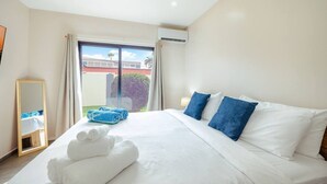 Quarto de hotel com cama grande, janela com cortinas, espelho e vista para o exterior.