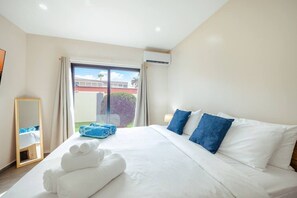 A hotel room with a large bed, a window with curtains, a mirror, and a view of the outside. - New Sea La Vie Suite # 3 |2BR|1BR W. Pool&Jacuzzi (Noord)