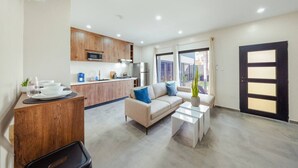 Um apartamento moderno com cozinha, sala de estar com sofá e mesa de centro, e uma janela grande.