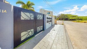 En grind markerar infarten till en fastighet, och en skylt visar att det är ”Palm Grove Suites”.