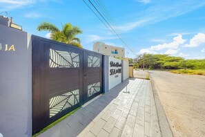 Ein verschlossenes Eingangstor zu einem Anwesen, auf dem ein Schild 'Palm Grove Suites' steht.