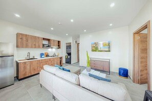 Eine moderne Küche mit Holzschränken, einer eingebauten Mikrowelle und einem Edelstahlkühlschrank.