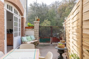 A patio area with a table and chairs, a brick wall, a wooden fence, and a gate. - Holiday Home “La Maison Blanche” with Private Terrace and Wi-Fi (Nazelles-Négron)