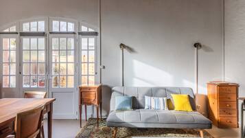 Una habitación con sofá, una mesa de madera, alfombra estampada y un armario.