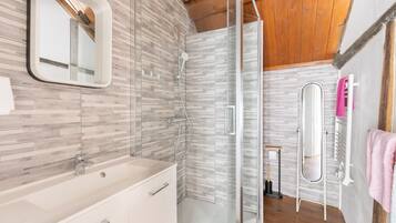 A modern bathroom with a glass shower enclosure, a white sink, and a mirror.